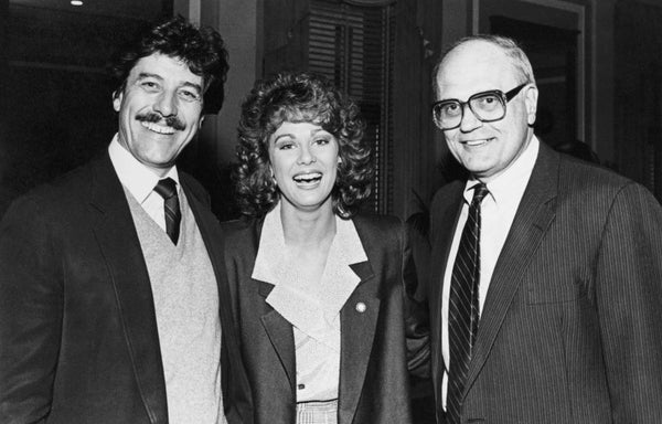 Kaye standing between two men